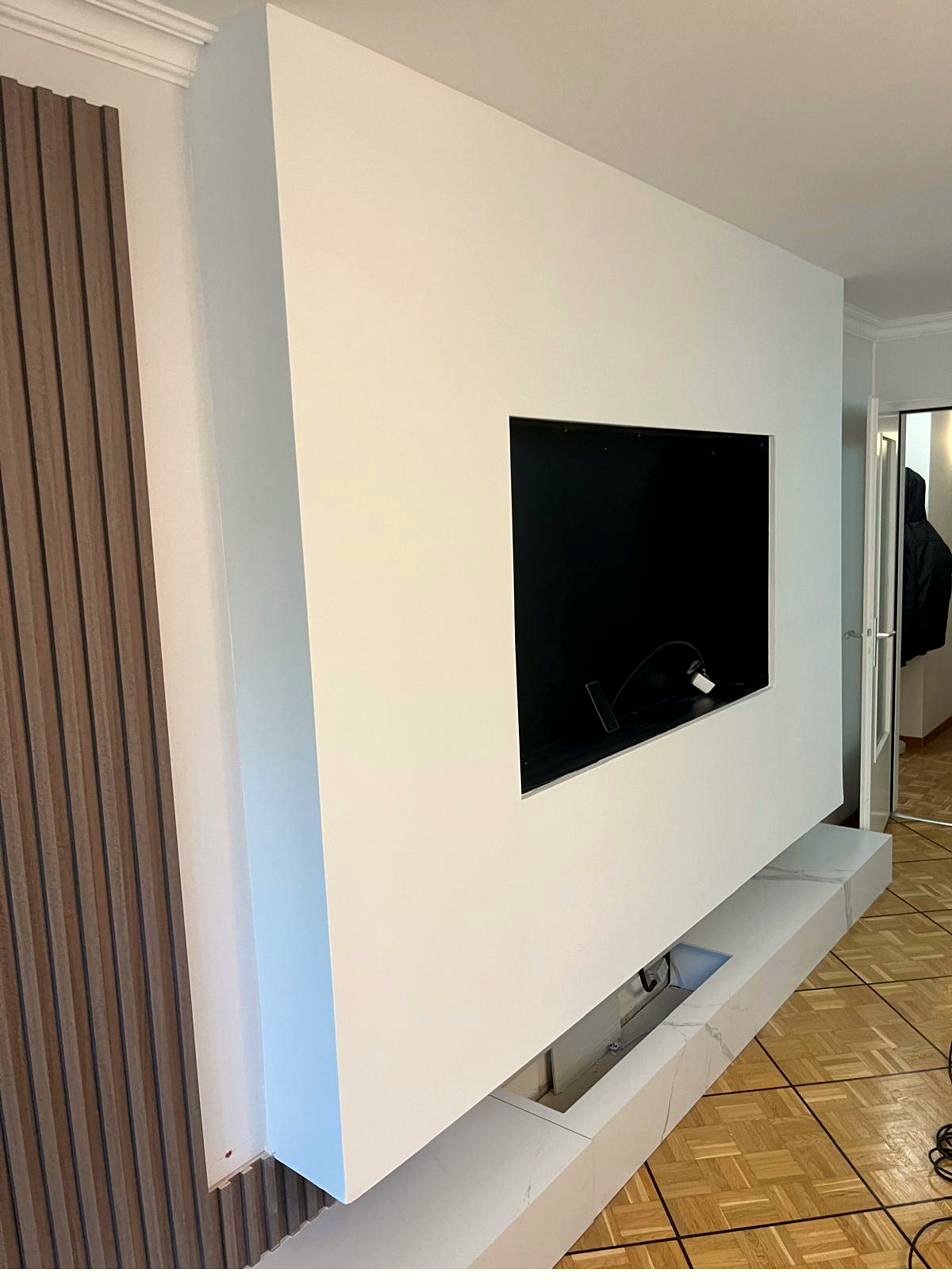 Custom TV feature wall painted in white with wood slat panelling, a JOAO DECO project in Geneva